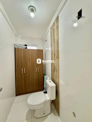 Banheiro com revestimento branco e armário de madeira.