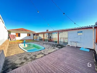 Vista externa de uma propriedade com piscina e deck de madeira.