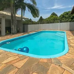 Foto de uma piscina azul em uma área externa de propriedade.