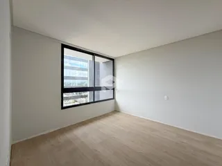Sala de estar com piso de madeira clara e grande janela.