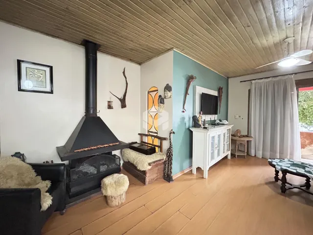 Sala de estar com lareira e piso de madeira clara em Lajeado.