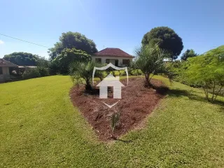 Vista da fachada da propriedade com jardim e vegetação.