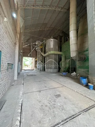 Vista interna de uma estrutura com vigas metálicas e paredes de alvenaria expostas.