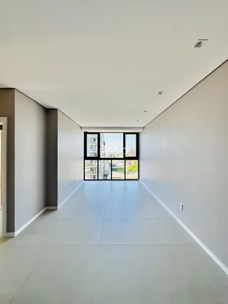 Corredor interno de um apartamento moderno com piso claro e grande janela.