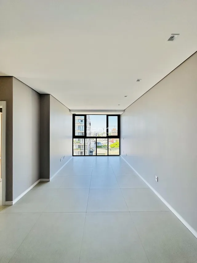 Corredor interno de um apartamento moderno com piso claro e grande janela.