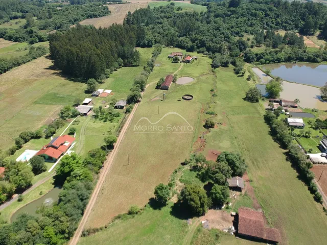 Vista aérea de uma propriedade rural com campos verdes e vegetação densa.