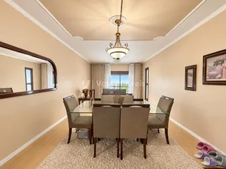 Sala de jantar com mesa de vidro e cadeiras em um ambiente claro.