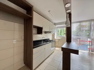 Cozinha moderna com armários brancos e bancada escura em um apartamento.