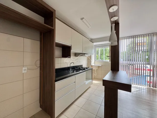 Cozinha moderna com armários brancos e bancada escura em um apartamento.
