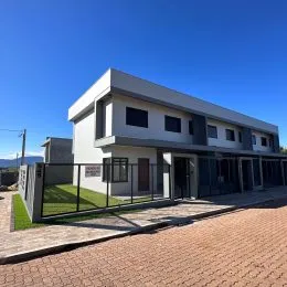Fachada de uma casa moderna com revestimento claro e detalhes escuros em Lajeado, Brasil.