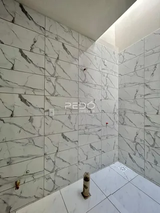 Parede revestida com azulejos brancos e cinzas em um ambiente interno.