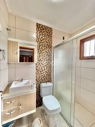 Foto de um banheiro interno com box de vidro e louças sanitárias.