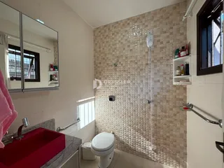 Foto interna de um banheiro com revestimento de mosaico bege.