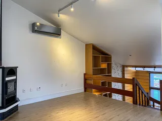 Sala de estar com piso de madeira e estante de madeira visível.