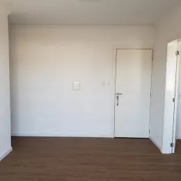 Foto de um corredor interno com paredes brancas e piso de madeira.