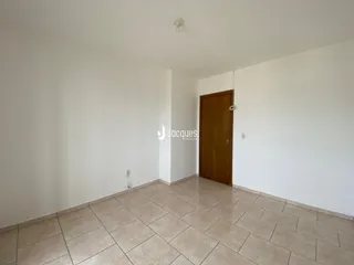 Hall de entrada com piso de cerâmica clara e porta de madeira.