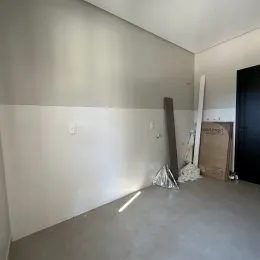 Foto de um ambiente interno com paredes brancas e piso claro.
