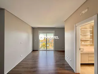 Corredor longo com piso de madeira e porta de vidro que dá para o exterior.