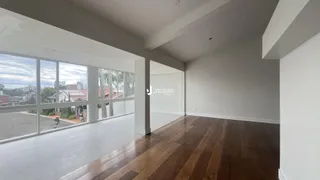 Sala de estar ampla com piso de madeira e grandes janelas.