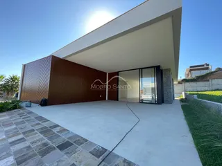 Fachada moderna de uma residência com revestimento de madeira e área externa de concreto.
