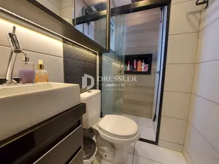 Interior de um banheiro com revestimento de cerâmica e box de vidro.