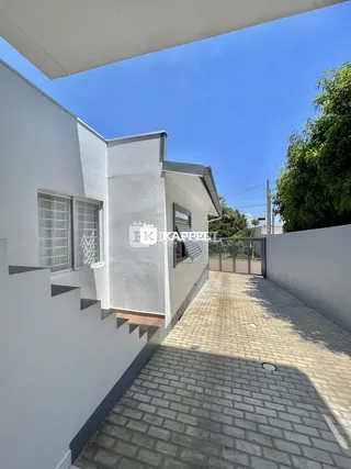 Fachada branca de uma residência em Lajeado com escadaria e calçada de tijolos.
