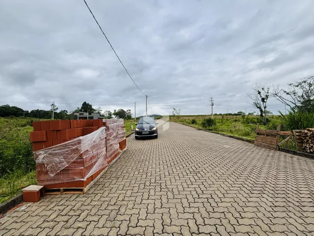 Uma estrada pavimentada com blocos de concreto e uma cerca de tijolos são visíveis na propriedade.
