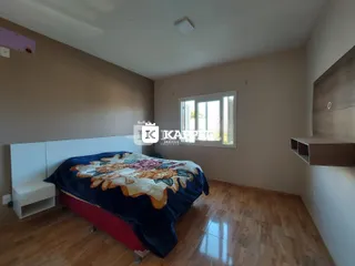 Quarto com cama e janela em um apartamento com piso de madeira.
