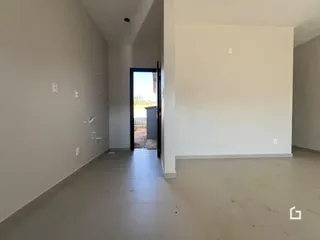 Corredor interno de uma residência com paredes brancas e piso claro.