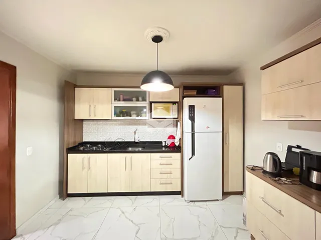 A cozinha apresenta armários de madeira e piso de mármore claro.