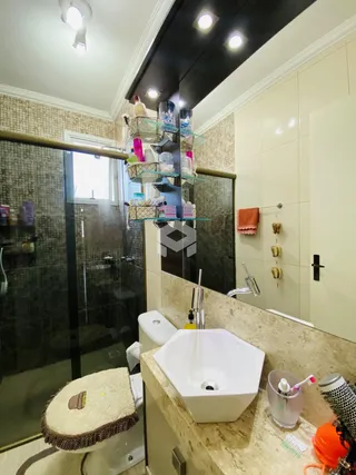 Foto de um banheiro com box de vidro e bancada de mármore.