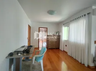Interior de uma sala com piso de madeira e paredes brancas.