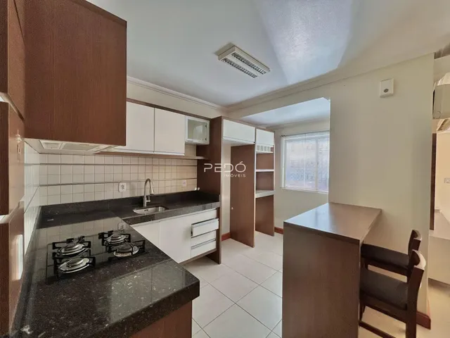 A cozinha apresenta armários brancos e bancadas escuras com piso de cerâmica.