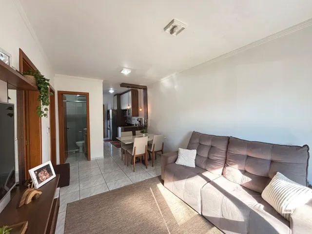 Sala de estar com sofá e acesso à cozinha em um imóvel em Lajeado.