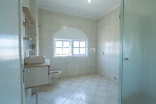 Foto interna de um banheiro com piso de cerâmica e paredes brancas.