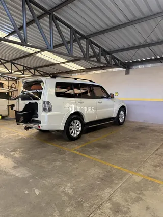Um veículo utilitário branco está estacionado em uma área de pátio industrial.
