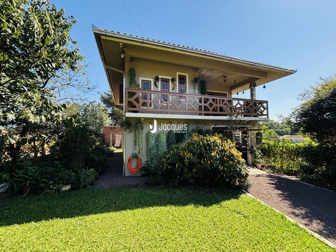 Fachada de uma casa em Lajeado, Brasil, com jardim exuberante e varanda.