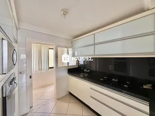 Cozinha moderna com armários brancos e bancadas escuras em um imóvel em Lajeado.