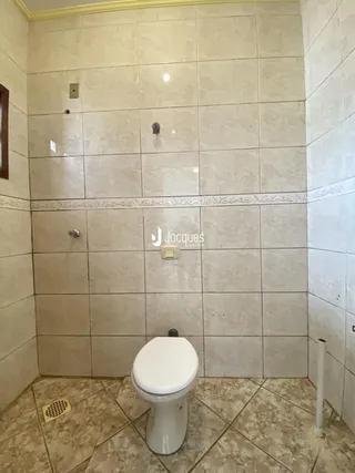 Banheiro com revestimento de azulejos claros nas paredes e piso.