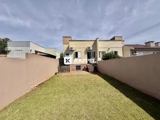 Vista externa de uma residência com um gramado frontal e muro alto.