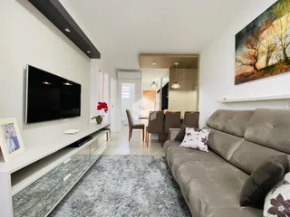 Sala de estar com sofá e televisão em um imóvel no Brasil.