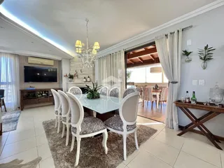 Uma sala de jantar iluminada com mesa e cadeiras brancas em um imóvel no Brasil.