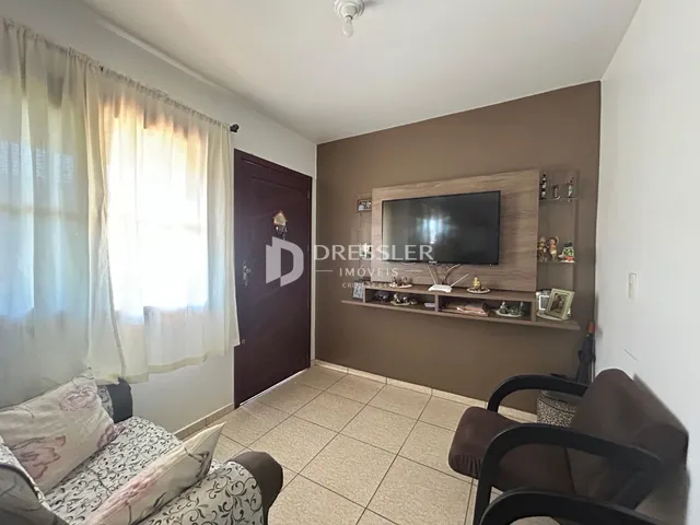 Sala de estar com cortinas claras e sofá no ambiente.