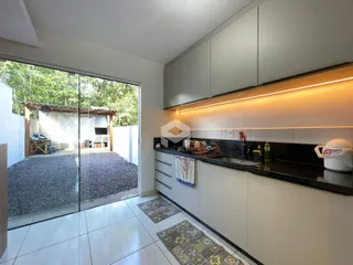 Cozinha com armários cinzas e bancadas pretas que se abre para uma área externa.