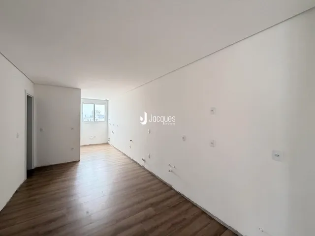 Corredor interno de uma residência com piso de madeira clara.