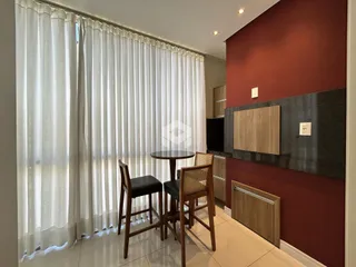 Ambiente interno com paredes vermelhas e cortinas brancas em uma sala de jantar.