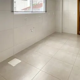 Foto de um corredor interno com paredes claras e piso de cerâmica.