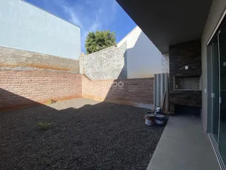 Vista externa da propriedade com parede de tijolos e área de jardim de cascalho.