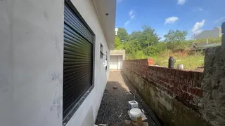 Vista da fachada de uma construção com parede branca e muro de tijolos.