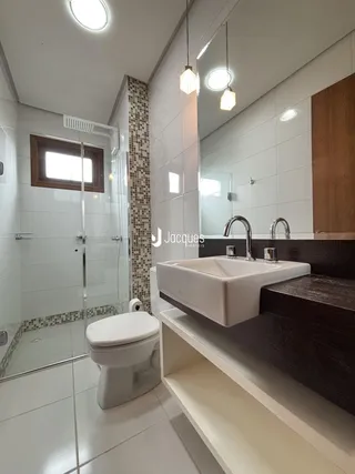 Banheiro moderno com box de vidro e piso de cerâmica.